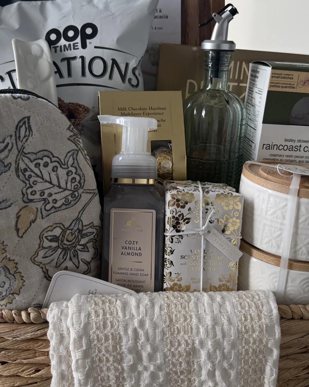 Welcome home basket with foaming hand soap, oil dispenser, popcorn, crisps and a waffle towel